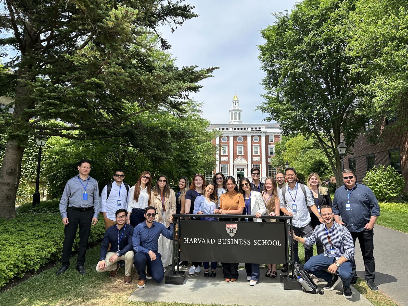 Grupo de participantes em frente à placa da Harvard Business School