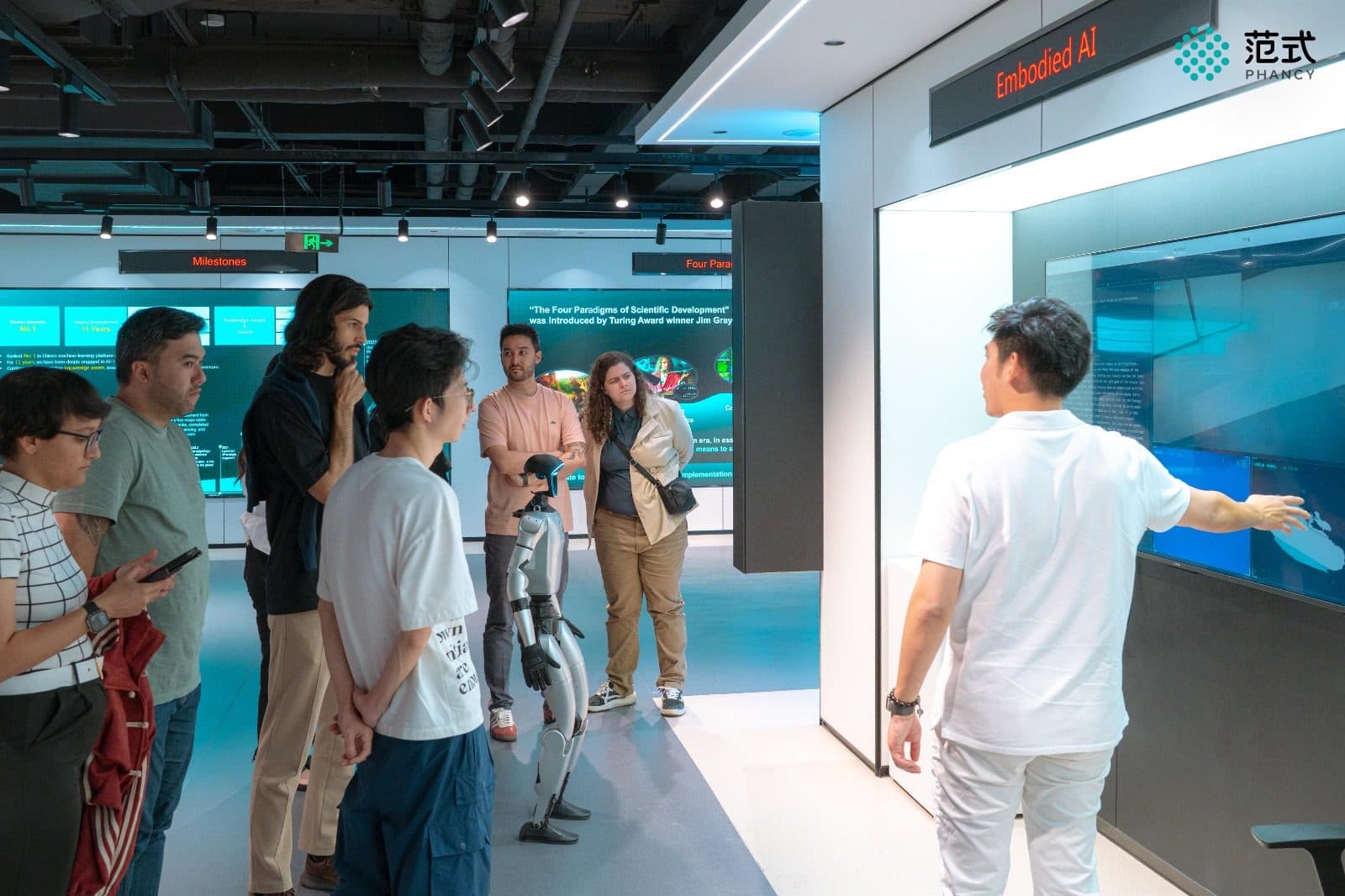Participantes observam um robô humanoide em centro de tecnologia